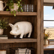 Vintage white crackle glazed ceramic pig figurine displayed on a rustic wood hutch shelf beside a potted plant overlooking prairie fields