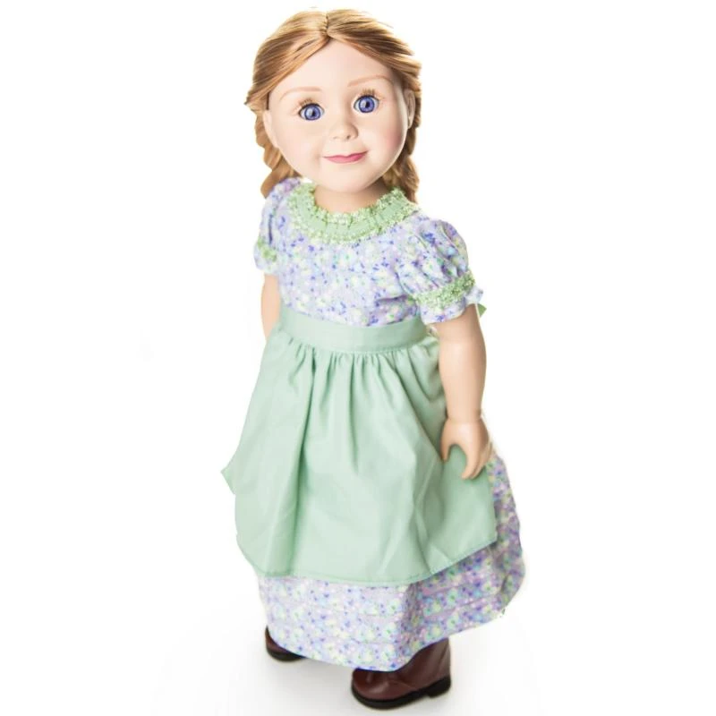 An 18-inch pioneer doll with braided blonde hair wearing a purple calico dress and green apron that fits 18" American Girl® Dolls made after 2008.