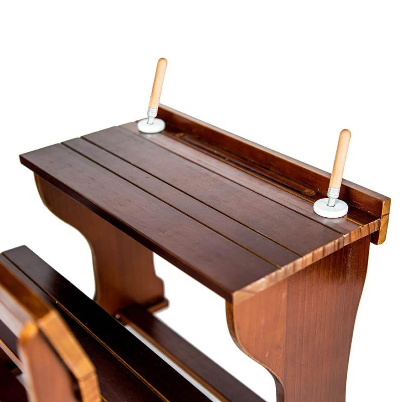 High-angle view of a miniature wooden pioneer school desk highlighting two stylus pens in their slots.
