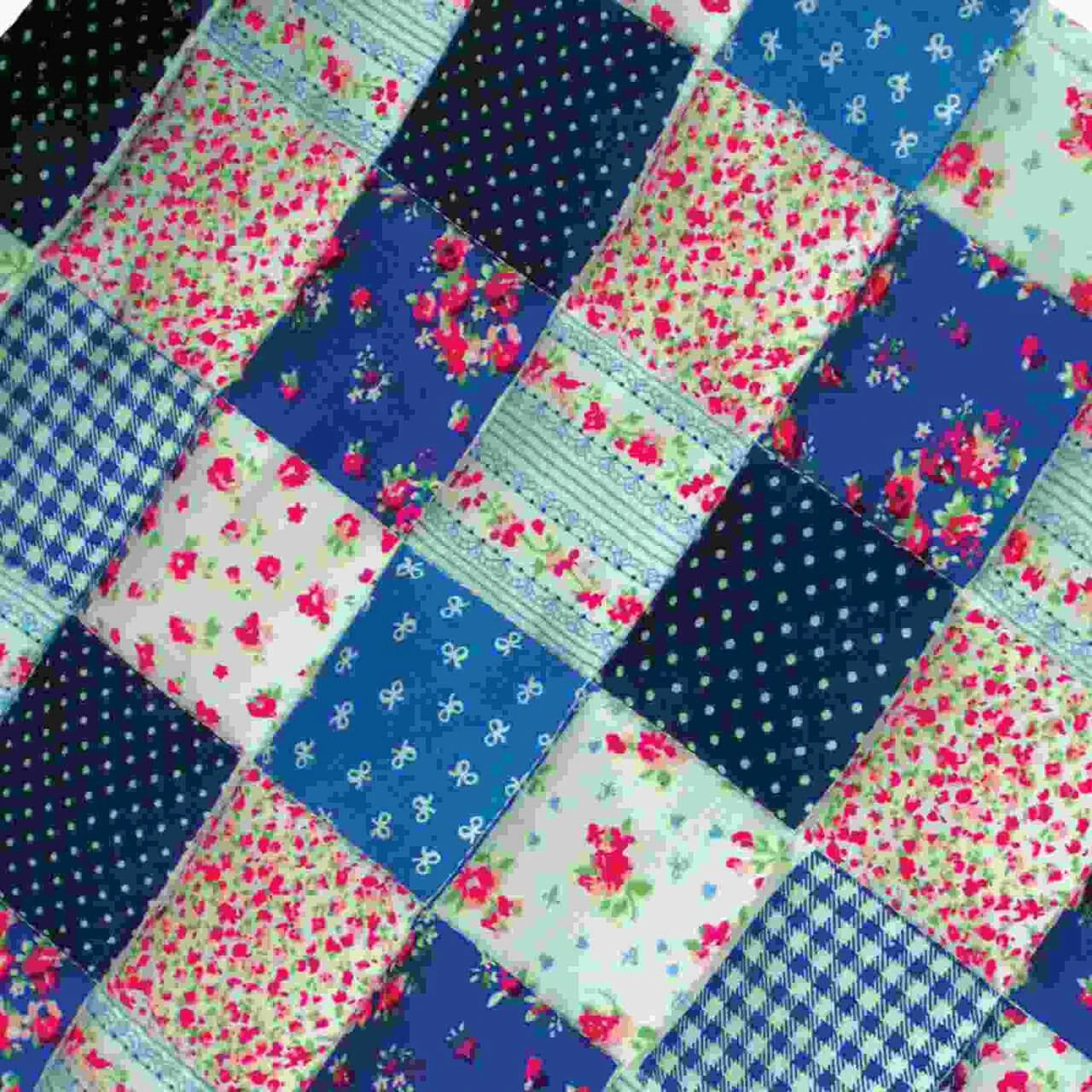 A close-up view of a doll patchwork quilt featuring alternating squares of blue polka dots, gingham, and floral patterns.