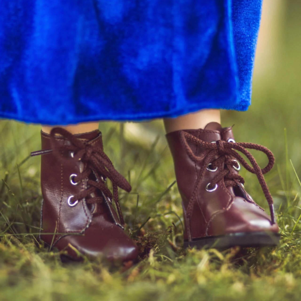 In outdoor scene the 18 inch doll shoes of brown lace up boots are modeled.