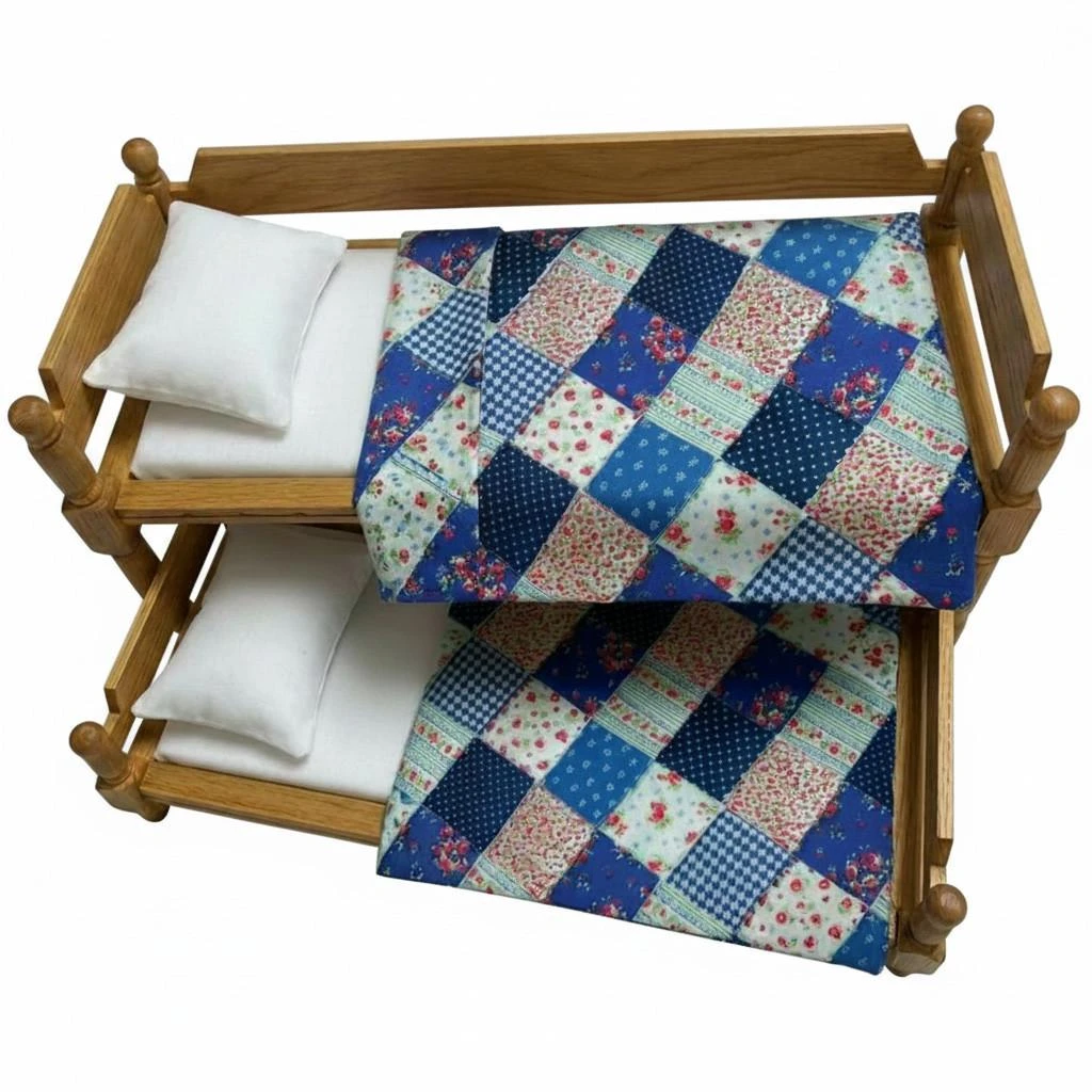 An 18-inch doll trundle bed with blue patchwork quilts set inside a miniature log cabin room alongside a braided rug, nightstand, and window.