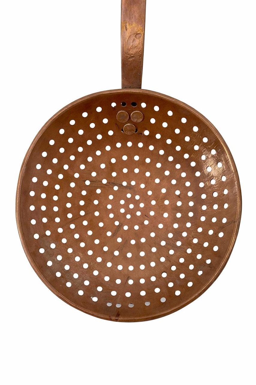 Underside angle of antique perforated copper skimmer showing bowl depth and handle connection
