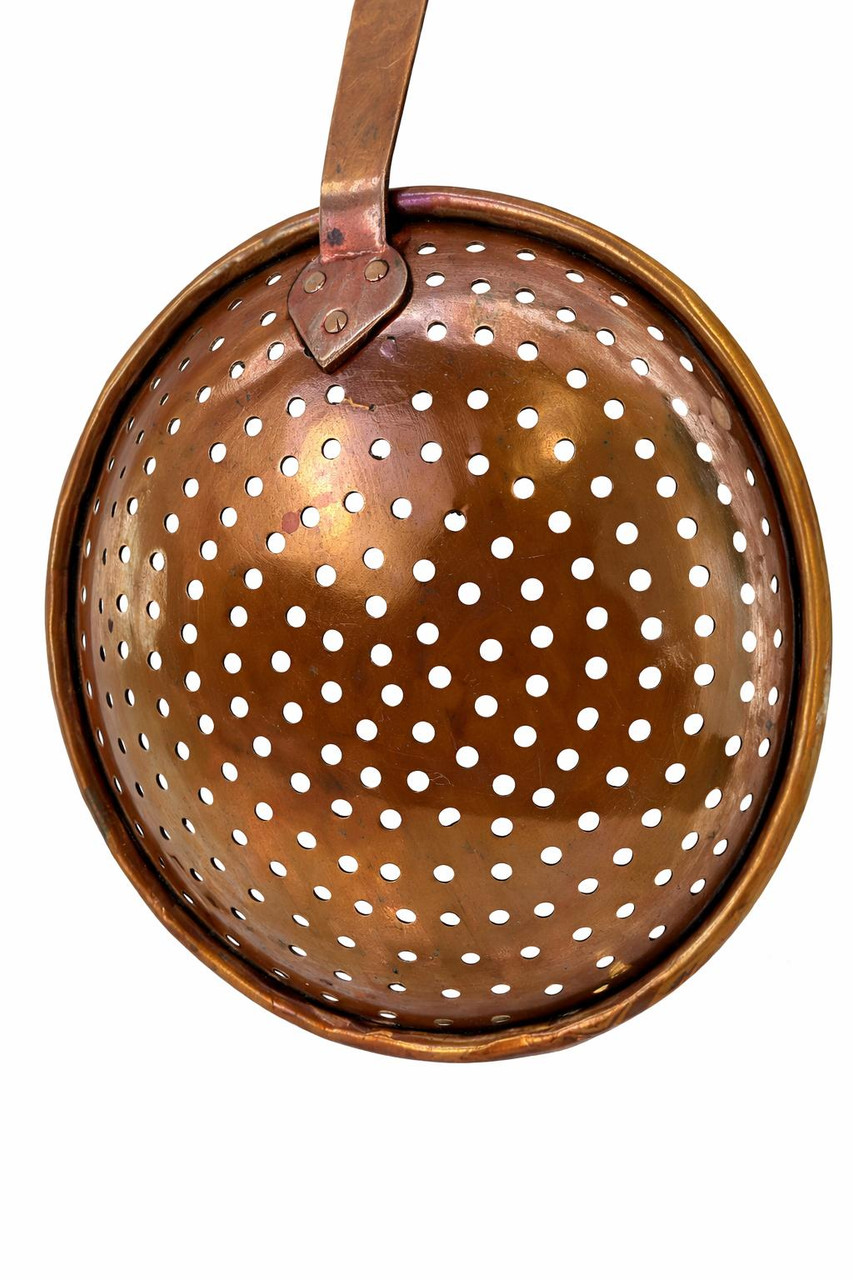 Close-up of three hand-set copper rivets and heart-shaped mount on back of strainer ladle