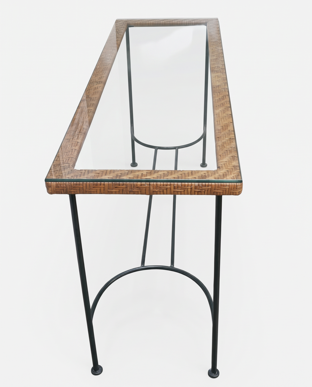 Overhead perspective looking down length of clear glass console table framed in natural woven rattan on stone terrace