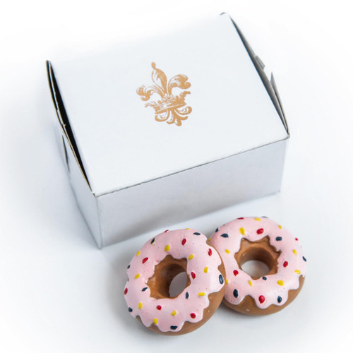 On white background there are 2 doll sized pink doughnuts and a bakery box with the Queen's Treasures fleur-de-lis embossed on top.