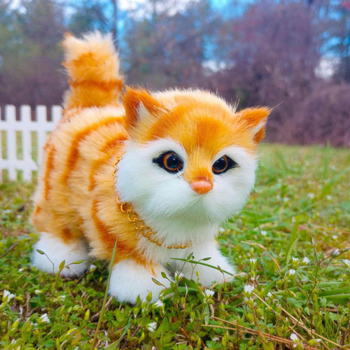 In outdoor scene the 18" doll pet of a orange tabby in close up.