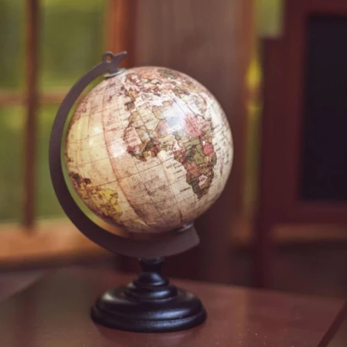 A close-up photograph displays a detailed miniature vintage-style desk globe designed for 18-inch doll displays.