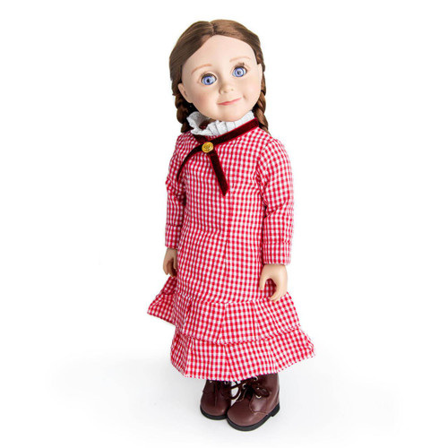 A pioneer doll with long brown hair in braids stands on a white background wearing a red and white checkered gingham dress with a dark red cross-ribbon collar and brown boots.