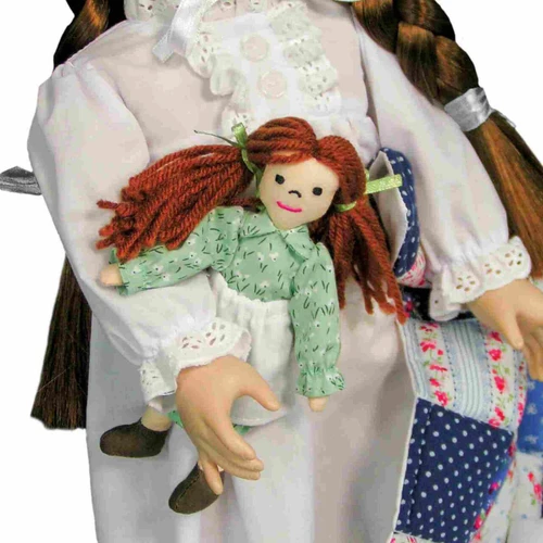 A close-up view of the 18-inch doll's hand holding a mini rag doll with yarn hair and a green dress.