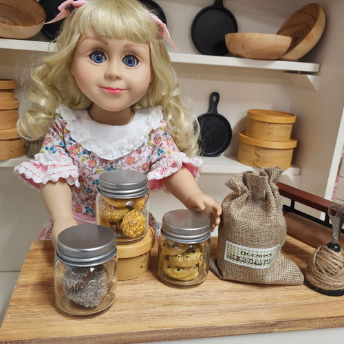 Nellie 18 inch doll standing at counter with 3 mini mason jars filled with 18 inch doll cookies.