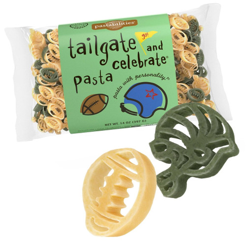 A single, horizontal clear bag of "Tailgate and Celebrate Pasta" by Pastabilities with a large green label showing a football and a blue helmet illustration. Positioned directly in front of the packaging are two enlarged pasta shapes—one light yellow football on the bottom left and one dark green football helmet on the right.