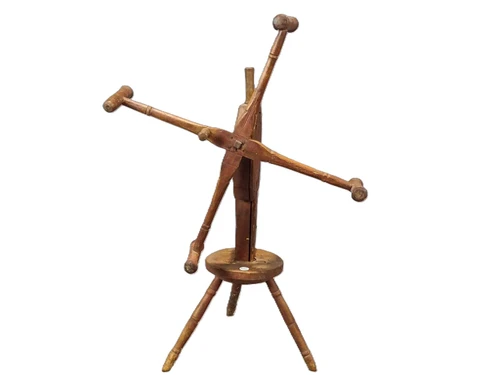 Side view of primitive wooden yarn winder showing the upright shaft, gear housing, and turned spindle