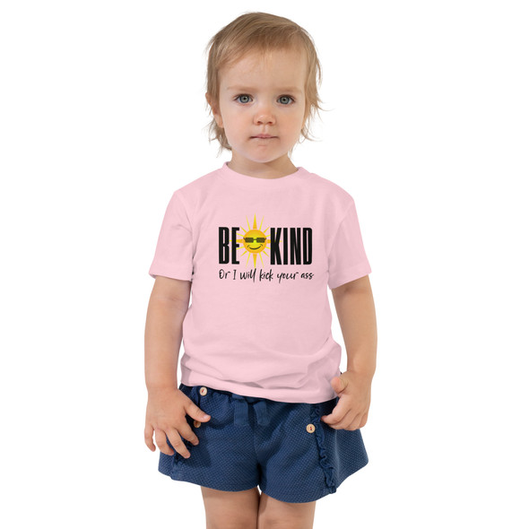 model wearing toddler T-shirt with the bold phrase "Be Kind or I Will Kick Your Ass" in playful letters, mixing humor and attitude for confident little adventurers.