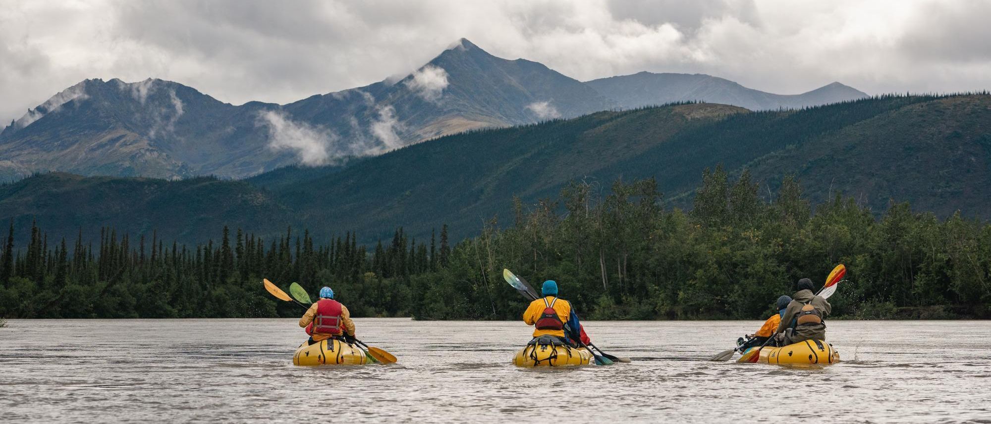 three people rowing in canoes