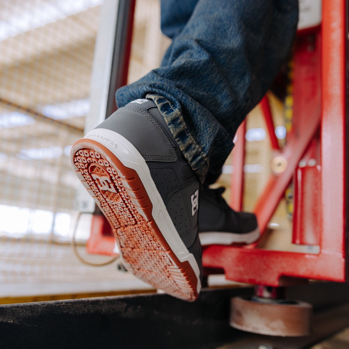 Worker climbing up on machinery wearing DC skate style work shoes.