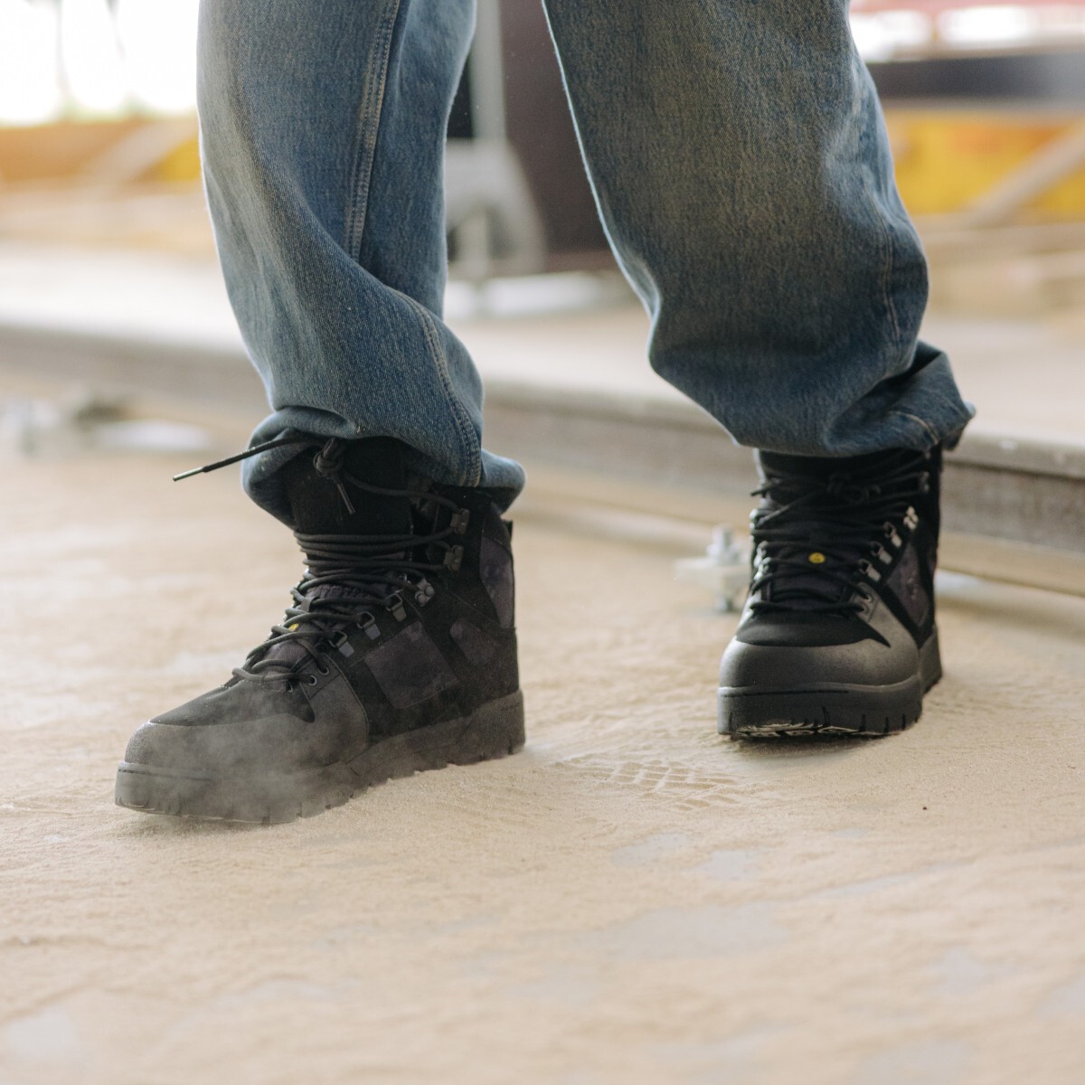 Worker wearing DC high top work shoes walking through a dusty job site.