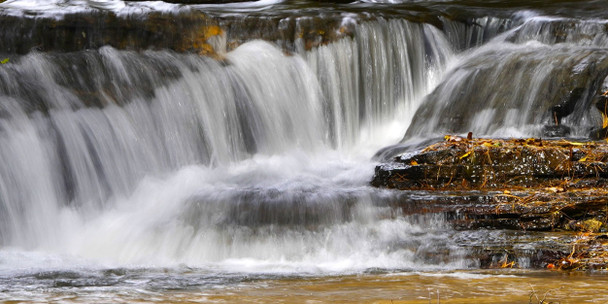 close-up of a small cataract with autumn leaves on the rocks