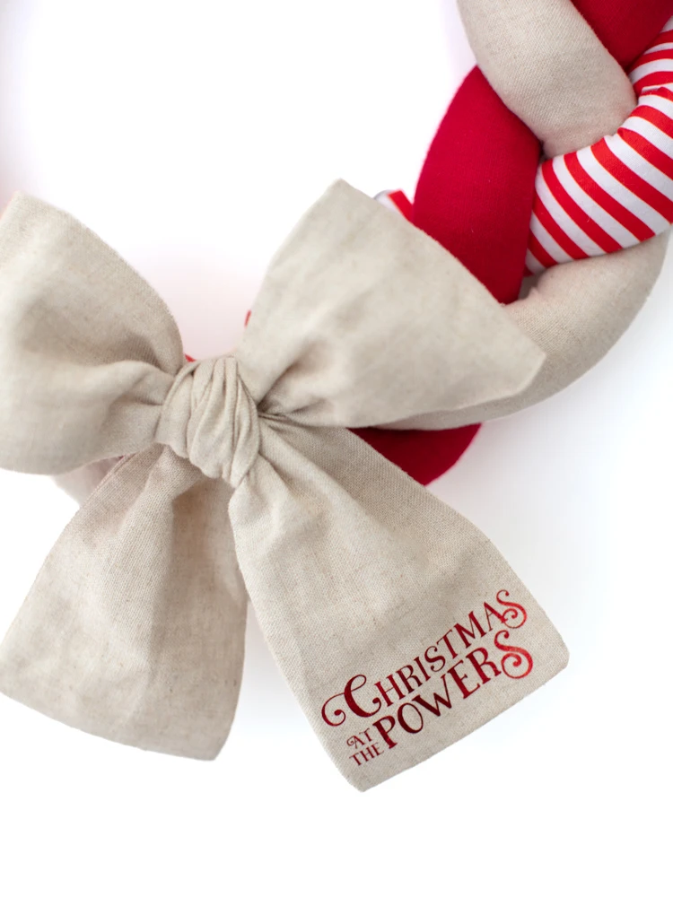 Close-up of oversized cream linen bow with red Christmas at the Powers lettering