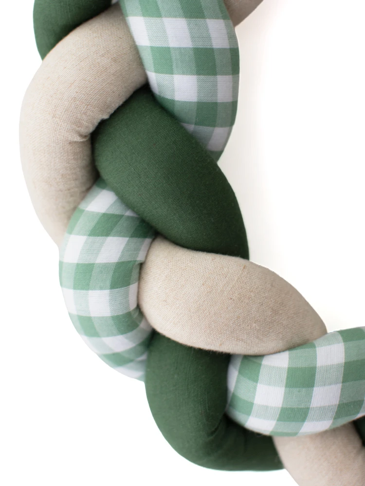 Close-up of handmade green Christmas wreath with plaited cream and gingham fabric