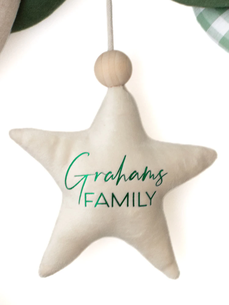 Close-up of cream Christmas star personalised with Grahams Family in green lettering