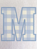 Close-up of the gingham print within the ‘M’, showcasing soft blue tones and a classic check pattern