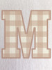 Close-up of the gingham print within the ‘M’, showcasing soft tan tones and a classic check pattern
