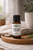 Essential7 Mind Body Balance 15 ml essential oil blend bottle displayed on a wooden board with soft neutral fabric and botanical greenery.