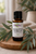 Essential7 Eucalyptus Globulus essential oil in an amber glass bottle with a black cap, displayed on a natural wooden stand and surrounded by fresh eucalyptus leaves in warm, softly diffused light.