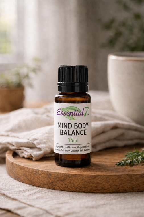 Essential7 Mind Body Balance 15 ml essential oil blend bottle displayed on a wooden board with soft neutral fabric and botanical greenery.