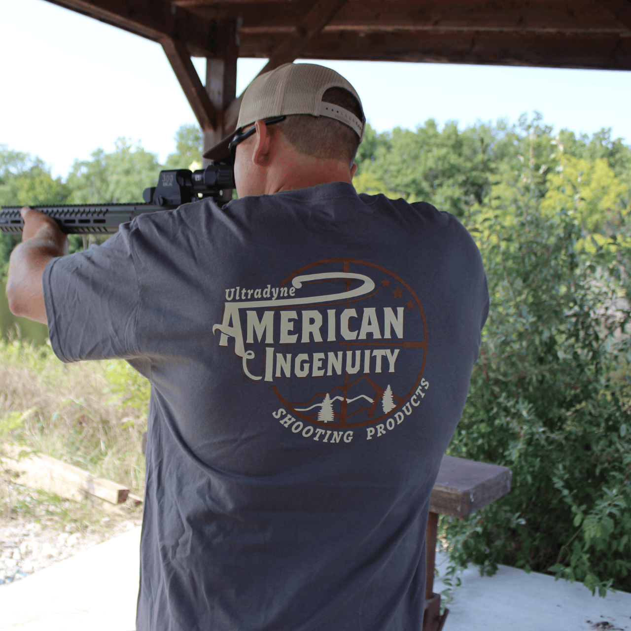 Man aiming a weapon displaying back of Ultradyne t-shirt