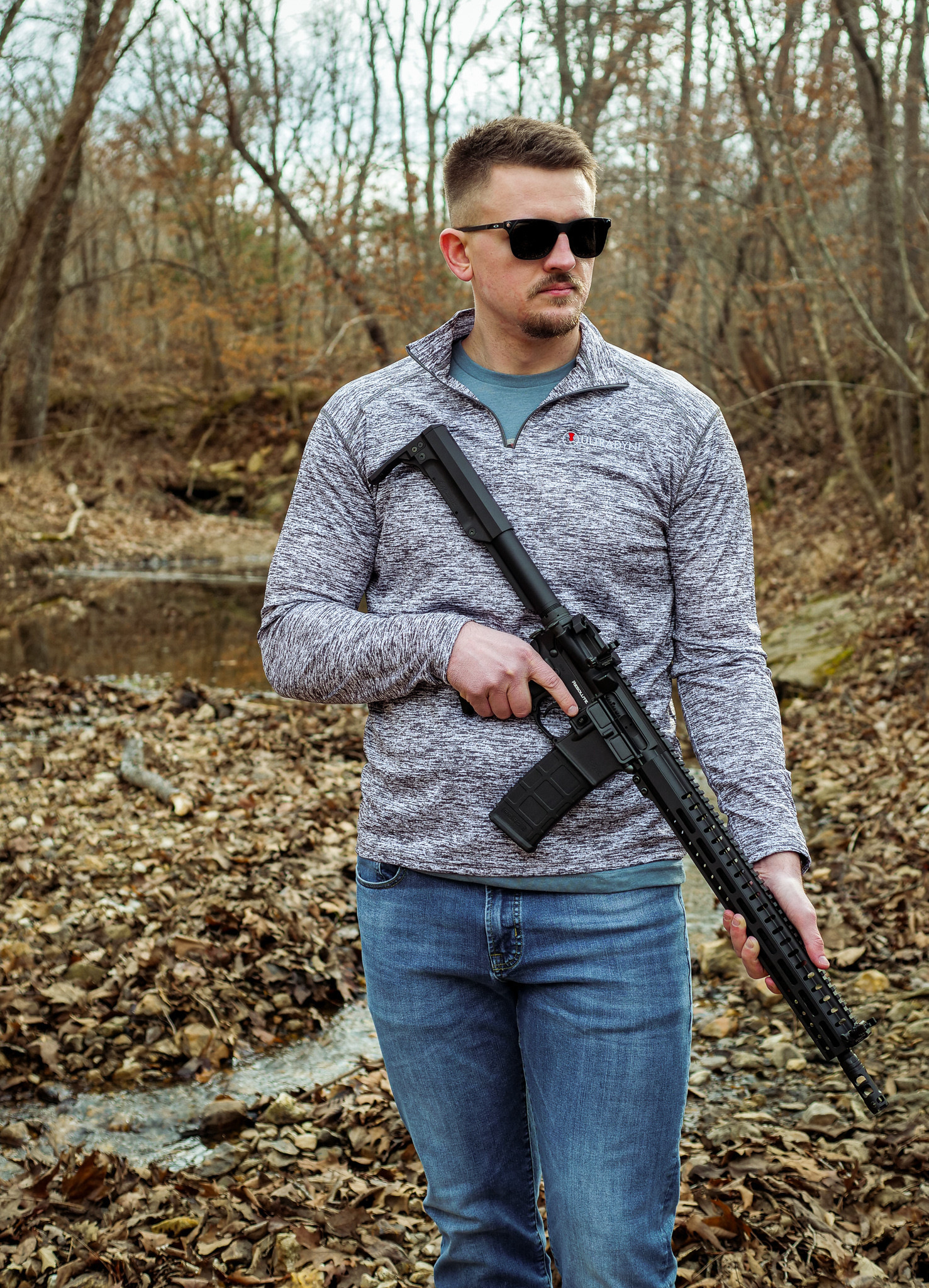 man holding rifle, wearing ultadyne quarter zip