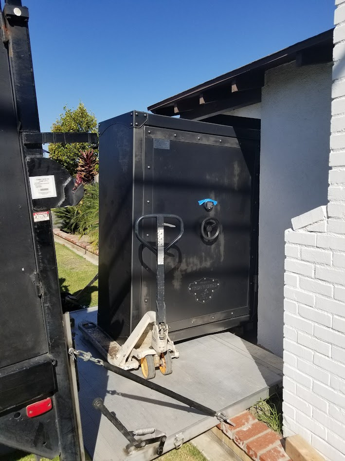 Boswell moving a large safe through a front door for final placement