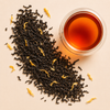 Bourbon Black Tea loose leaf blend with black tea, golden sunflower petals, calendula petals, and a cup of amber brewed tea.