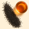 Ceylon Sonata loose leaf black tea with a cup of bright amber brewed tea on a warm cream background.