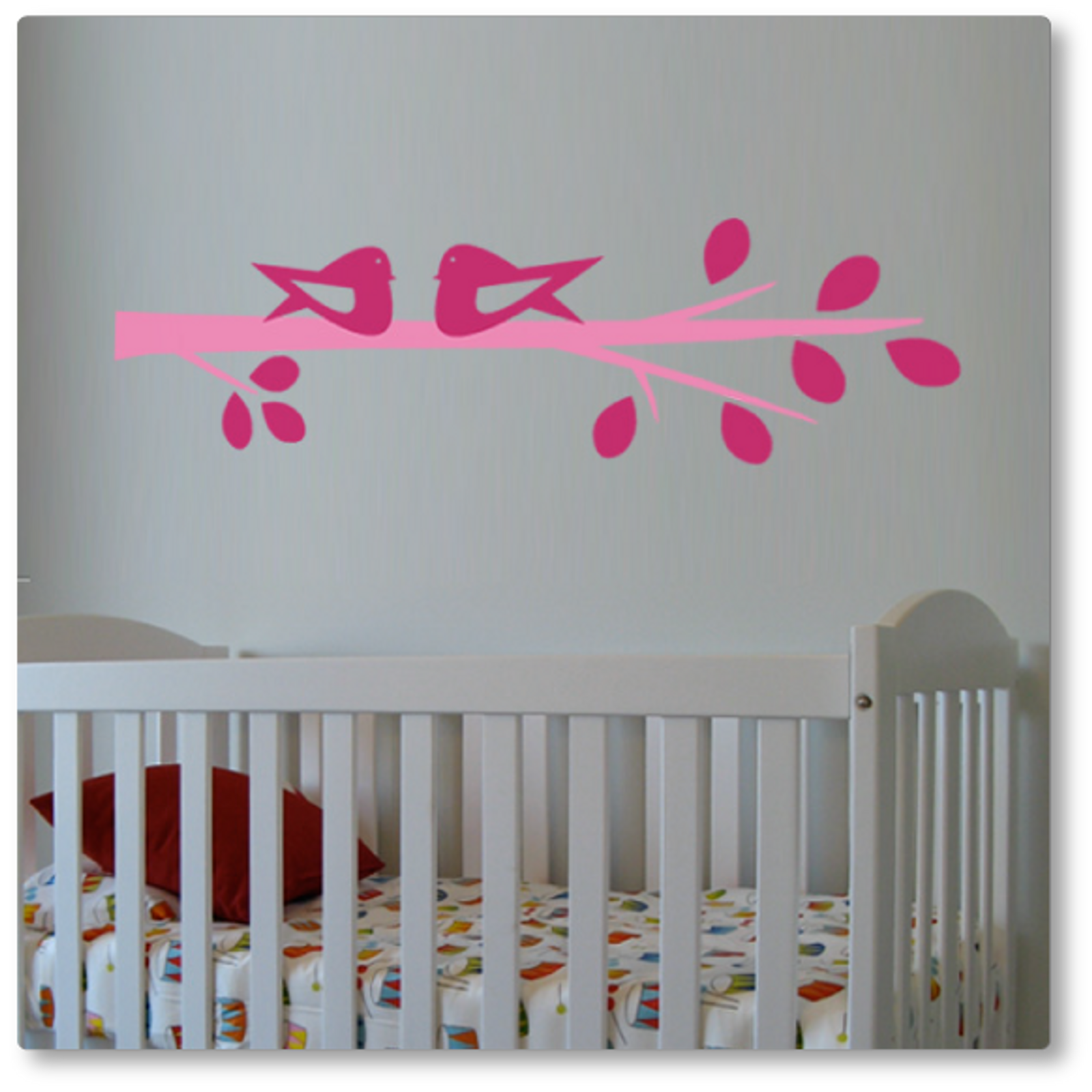Our cute birds on a branch wall decal features two birds sitting on a branch with leaves. Shown here in pink and light pink on a beige wall.