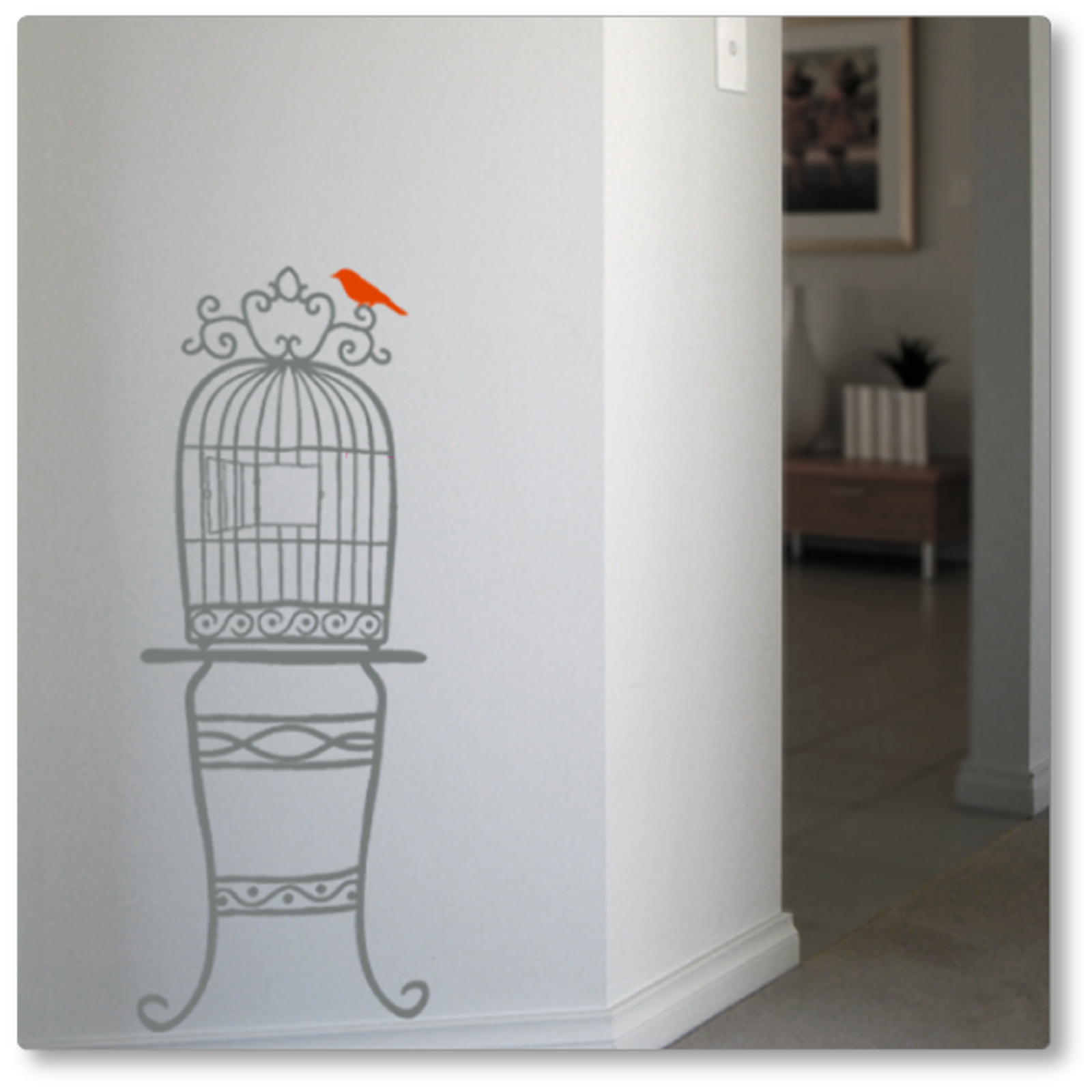 Our quirky birdcage on a table was adapted from a hand drawn image. It adds flair to any wall. Shown in grey, red bird, on a neutral wall.