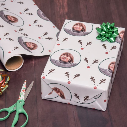 Personalized Christmas wrapping paper has reindeer antlers, red nose and is personalized with of your choice.