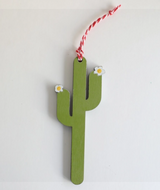 green saguaro cactus with small white flowers on the tips and a white and red hanger