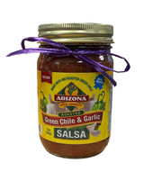 Glass jar with red salsa with a yellow label with a picture of garlic and peppers.