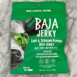 green pouch bag with half of a cows face on the left side. the cow is wearing sunglasses with a reflection of green sunglasses. "Baja Jerky" is boldly written across the top with product information underneath