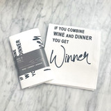 a marble countertop with a white towel laying on top on it, folded in half with the text in a typewriter font. For the full text please see product description. Next to the towel is the folded version of the same towel with a gray band around it with the Dev D and Co. logo