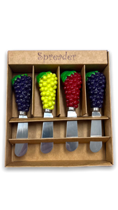 Four grape shaped handle of cheese spreaders in green, red and two in purple in a tan display gift box. Four grape shaped handle of cheese spreaders in green, red and two in purple in a tan display gift box.