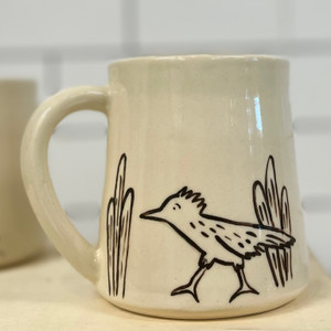 Light tan mug with handle with drawing of roadrunner and cacti