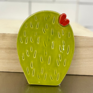 Light green, ceramic spoon rest in the shape of a prickly pear cactus pad.