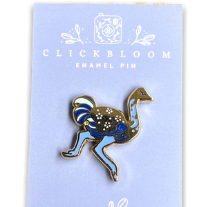 Enamel pin in the shape of a ostrich in shades of blue and gold.