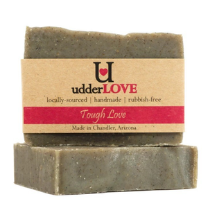 Dark gray bar of soap with tan paper wrapping with black and pink lettering