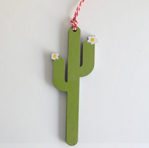 green saguaro cactus with small white flowers on the tips and a white and red hanger
