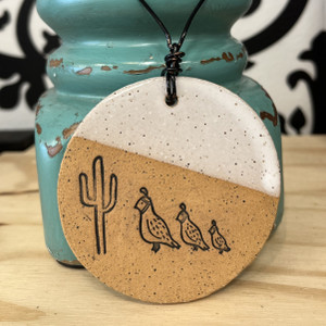 A round ornament half white, half rustic brown in color. Featuring three different size quail and a tall saguaro cactus