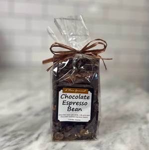 Clear cello food bag showing contents of dark chocolate bark with square white front label tied with a bow.